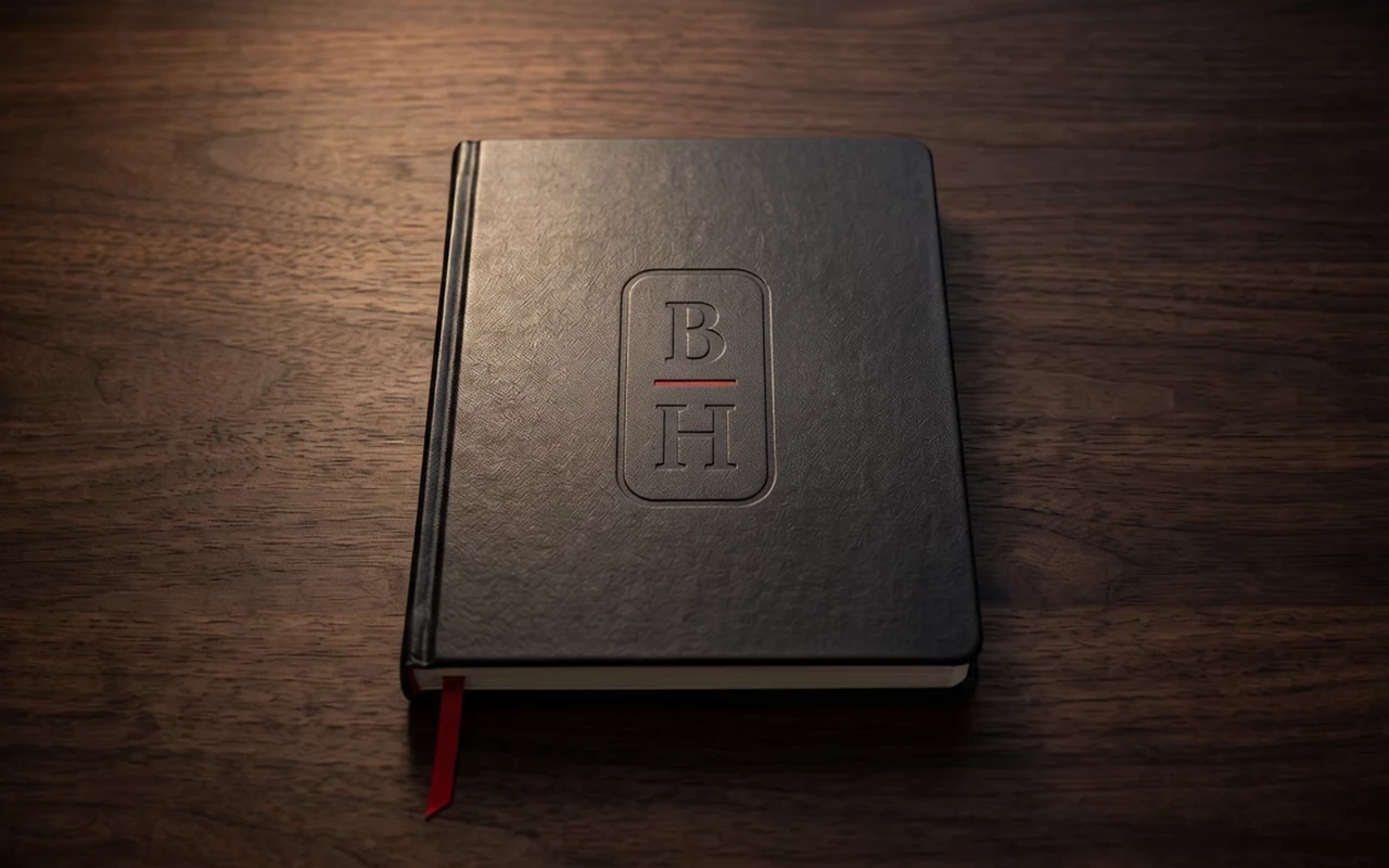 A closed black notebook on a walnut desk in warm light